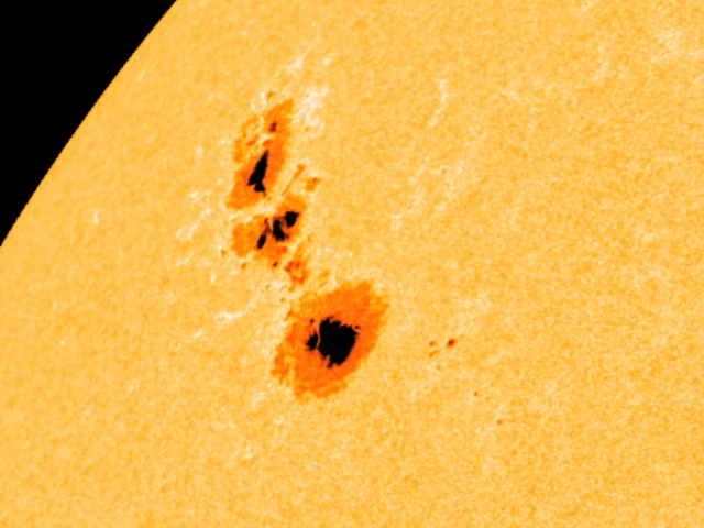 A portion of the orange Sun with a few dark orange splotches with black spots in the middle